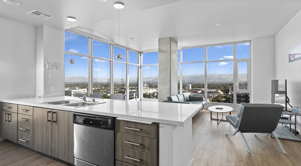 The Grad San Jose apartment interior kitchen and living room area with view from floor to ceiling windows